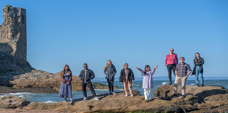 students standing on rocks at beach