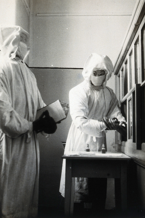 Historic image with researchers wearing protective clothing and masks