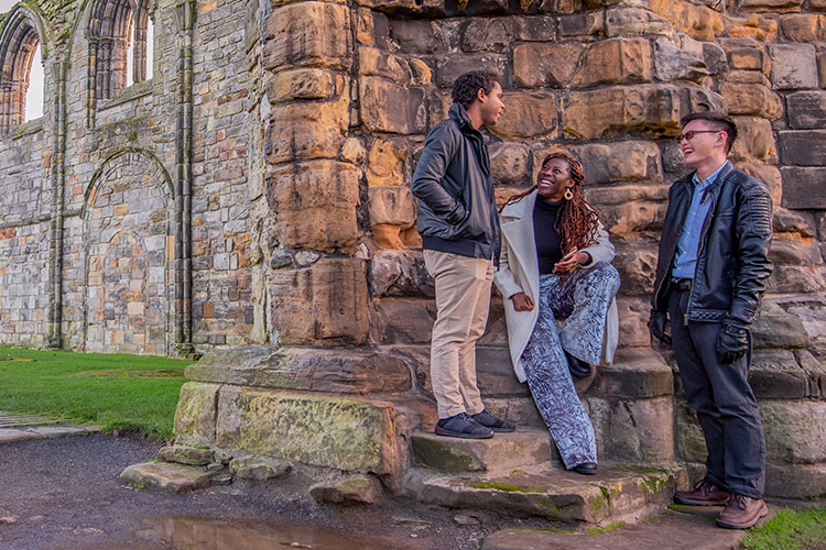 Three students standing outside Cathedral ruins 