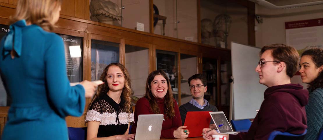 Group of students sitting around a table with a tutor