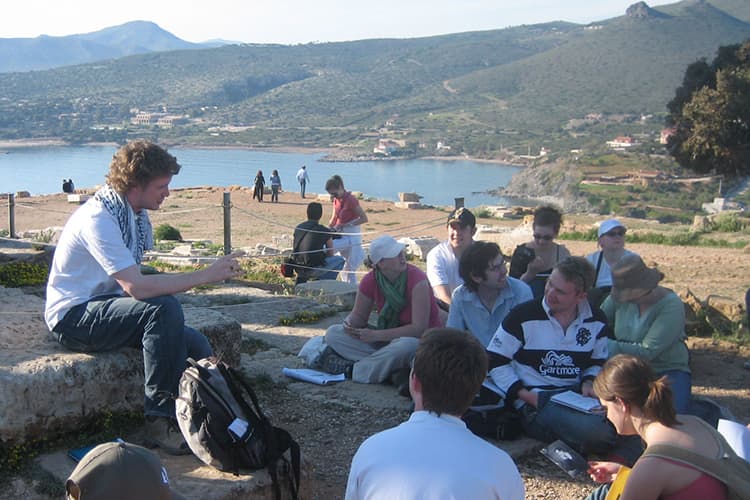 Students sitting outside in the sun discussing their work