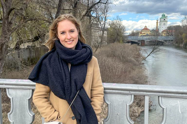 Rebecca Hummelsberger, 2021 winner of the Peter Grinyer PGT Prize for the MLitt Management, shown on a bridge with in an historic autumn riverside view