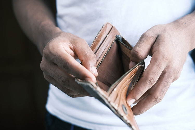 hands of a man holding open an empty brown leather bifold wallet