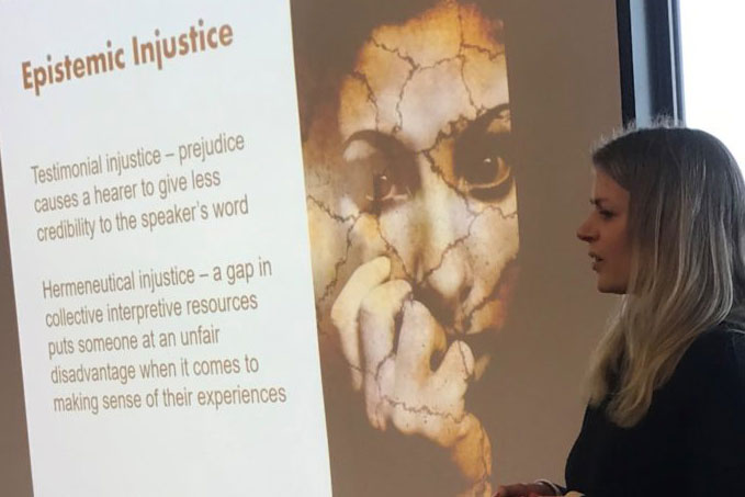 Jenna Breckenridge, presenter at RURU workshop November 2022, in front of a projector screen with slide showing 