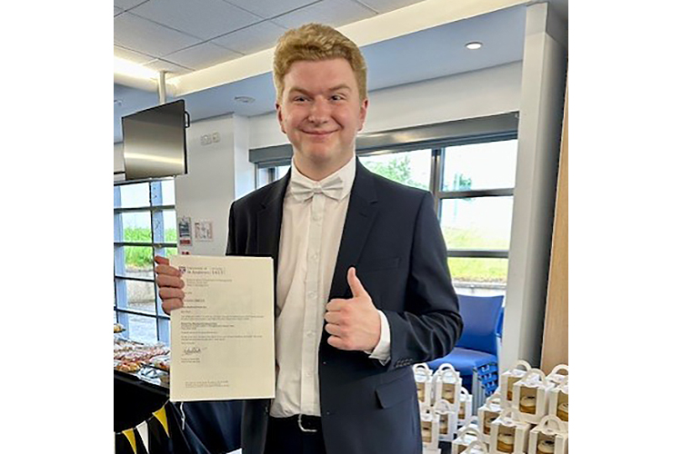 Oliver Gardner holding his Nisbet Prize certificate and giving thumb up