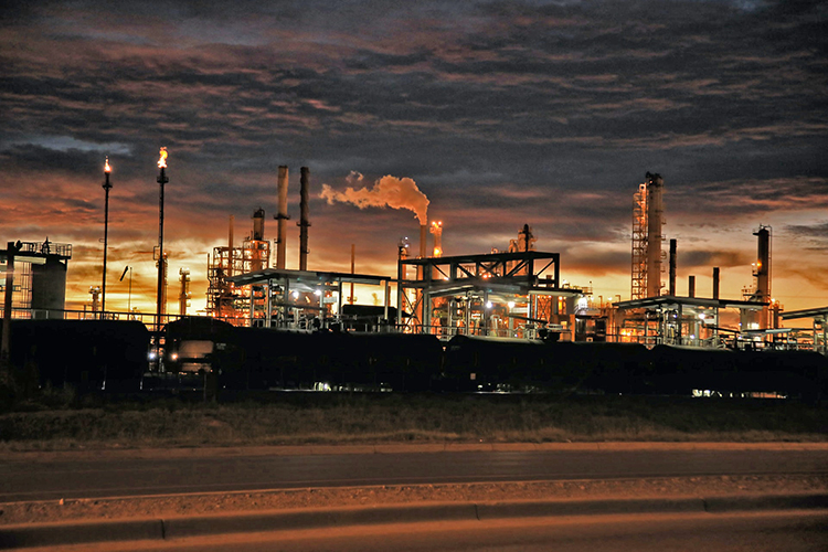 refinery in Artesia, NM, USA, shown against heavy clouds in the sky and colours of sunrise or sunset