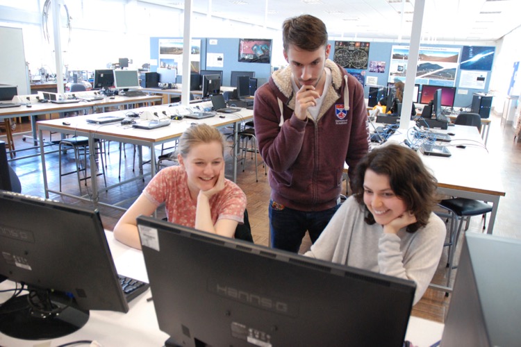 Three students performing calculations on a computer in the astro lab. 