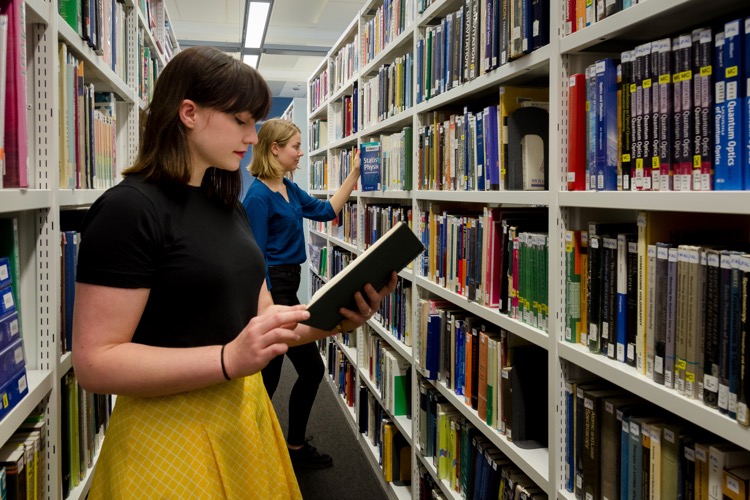 Two students in the library looking at books.