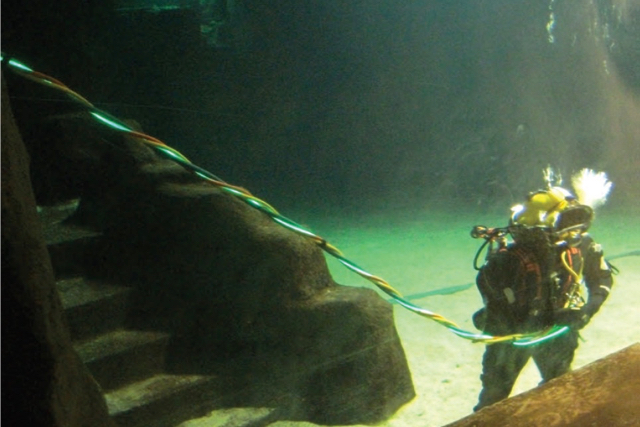 North Sea diver with umbilical cable, that is emitting light.