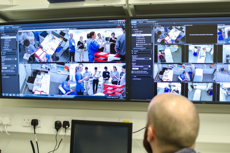 Two computer screens showing footage of people in a lab