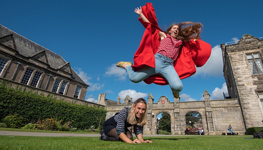 student leaping over other student