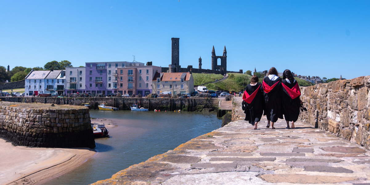 Three graduates walking on the pier in gowns